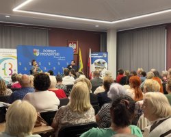 Szerokie ujęcie nowoczesnej, jasnej sali wypełnionej uczestnikami wydarzenia. Na samym końcu sali widać scenę, na której trwa rozmowa z Katarzyną Skrzynecką